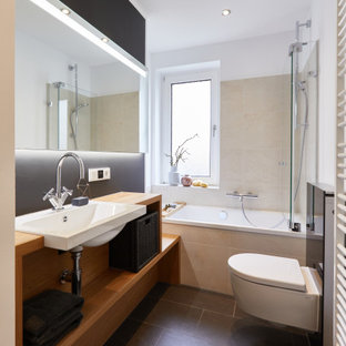 Mittelgroßes Modernes Duschbad mit offenen Schränken, hellbraunen Holzschränken, Einbaubadewanne, Duschbadewanne, Wandtoilette, beigefarbenen Fliesen, Keramikfliesen, schwarzer Wandfarbe, Schieferboden, Einbauwaschbecken, schwarzem Boden, Falttür-Duschabtrennung, brauner Waschtischplatte, Waschtisch aus Holz, Einzelwaschbecken und schwebendem Waschtisch in Hannover