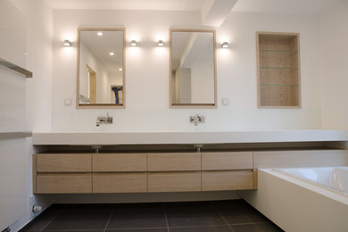 Imagen de cuarto de baño minimalista de tamaño medio con armarios con paneles lisos, puertas de armario de madera clara, baldosas y/o azulejos de vidrio laminado, paredes blancas, lavabo de seno grande y encimera de acrílico
