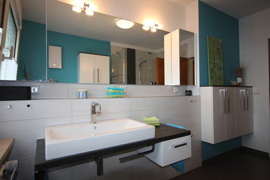 Mittelgroßes Modernes Badezimmer mit weißen Schränken, Eckdusche, grauen Fliesen, blauer Wandfarbe, Porzellan-Bodenfliesen und Aufsatzwaschbecken in Köln
