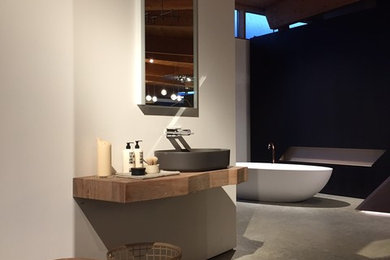 Großes Modernes Badezimmer En Suite mit Waschtisch aus Holz, freistehender Badewanne, weißer Wandfarbe, Betonboden, Aufsatzwaschbecken und grauem Boden in München