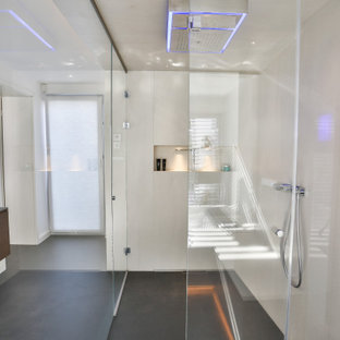 Design ideas for a large contemporary master bathroom in Frankfurt with flat-panel cabinets, dark wood cabinets, a freestanding tub, a curbless shower, a wall-mount toilet, beige tile, stone tile, beige walls, slate floors, an integrated sink, glass benchtops, black floor, an open shower, grey benchtops, an enclosed toilet, a double vanity, a floating vanity, wallpaper and wallpaper.