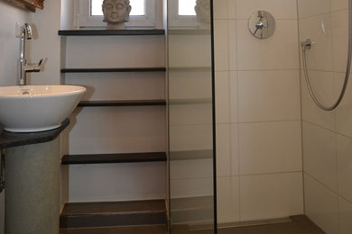 Kleines Shabby-Look Duschbad mit braunen Schränken, bodengleicher Dusche, weißen Fliesen, weißer Wandfarbe, Porzellan-Bodenfliesen, Aufsatzwaschbecken, Beton-Waschbecken/Waschtisch, schwarzem Boden, Falttür-Duschabtrennung, brauner Waschtischplatte, Einzelwaschbecken und freistehendem Waschtisch in München