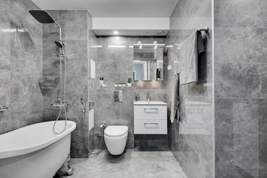 Exempel på ett mellanstort modernt badrum med dusch, med vita skåp, ett fristående badkar, en vägghängd toalettstol, grå kakel, keramikplattor, klinkergolv i keramik och grått golv