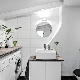 Idéer för att renovera ett minimalistiskt beige beige badrum med dusch, med släta luckor, vita skåp, en toalettstol med separat cisternkåpa, vit kakel, vita väggar, ett fristående handfat, träbänkskiva och svart golv
