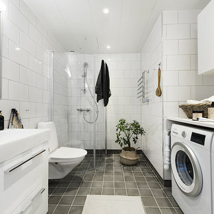 Inspiration för ett skandinaviskt vit vitt badrum med dusch, med släta luckor, vita skåp, en hörndusch, en toalettstol med separat cisternkåpa, vit kakel, ett integrerad handfat, grått golv och dusch med gångjärnsdörr