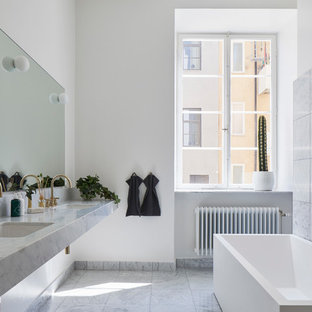 Exempel på ett skandinaviskt grå grått en-suite badrum, med ett fristående badkar, grå kakel, vita väggar, ett väggmonterat handfat och grått golv