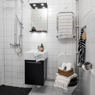 Bild på ett litet nordiskt vit vitt badrum med dusch, med släta luckor, svarta skåp, en hörndusch, en toalettstol med hel cisternkåpa, vit kakel, ett integrerad handfat, vitt golv och med dusch som är öppen