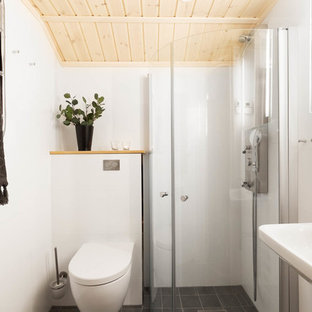 Idéer för ett minimalistiskt badrum, med en hörndusch, en vägghängd toalettstol, vit kakel, vita väggar, ett väggmonterat handfat, grått golv och dusch med skjutdörr