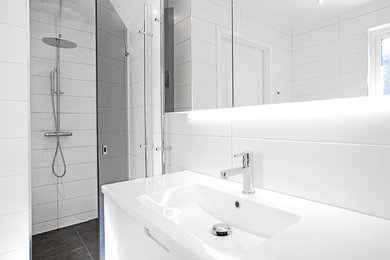 This is an example of a medium sized modern shower room bathroom in Malmo with white cabinets, white tiles, cement tiles, wooden worktops, an alcove shower, a trough sink, a hinged door, a two-piece toilet, white walls, ceramic flooring and multi-coloured floors.