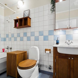 Skandinavisk inredning av ett badrum, med luckor med infälld panel, skåp i mellenmörkt trä, ett platsbyggt badkar, en dusch/badkar-kombination, blå kakel, vit kakel, beige väggar, ett nedsänkt handfat, blått golv och dusch med duschdraperi