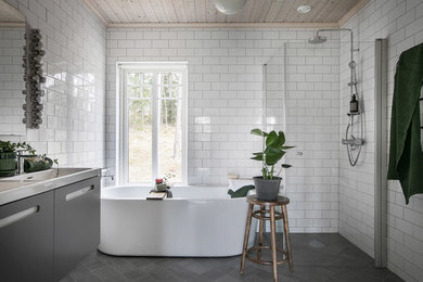 Idéer för att renovera ett minimalistiskt vit vitt en-suite badrum, med släta luckor, grå skåp, ett fristående badkar, en kantlös dusch, vit kakel, tunnelbanekakel, ett nedsänkt handfat, grått golv och dusch med gångjärnsdörr
