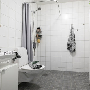 Exempel på ett minimalistiskt badrum med dusch, med släta luckor, vita skåp, en kantlös dusch, vit kakel, vita väggar, ett väggmonterat handfat, grått golv och dusch med duschdraperi
