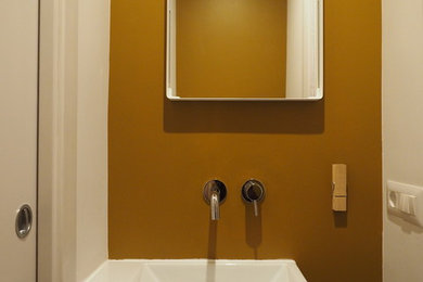 Réalisation d'un petit WC et toilettes design avec WC à poser, un mur vert, parquet clair et une grande vasque.