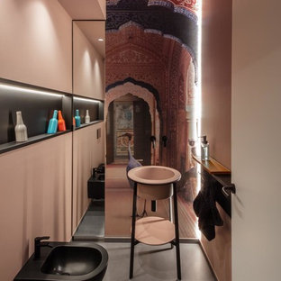 Foto på ett mellanstort funkis rosa toalett, med svarta skåp, en toalettstol med separat cisternkåpa, grå kakel, rosa väggar, klinkergolv i porslin, ett piedestal handfat, bänkskiva i akrylsten och grått golv