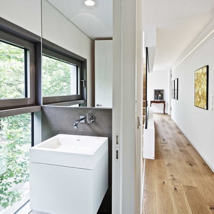 Ispirazione per un bagno di servizio moderno con ante lisce, ante bianche, pareti bianche, lavabo a consolle e pavimento grigio