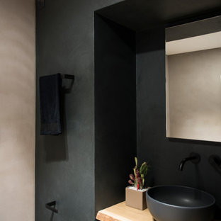 Ispirazione per un bagno di servizio design di medie dimensioni con WC sospeso, piastrelle nere, pareti nere, top in legno e mobile bagno sospeso