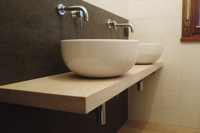 Immagine di un bagno di servizio minimalista con piastrelle bianche, piastrelle in ceramica, pareti bianche, lavabo a bacinella e top in legno