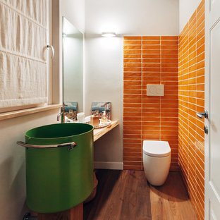 Idee per un piccolo bagno di servizio design con piastrelle arancioni, piastrelle in ceramica, parquet scuro, WC sospeso, pareti bianche e pavimento marrone