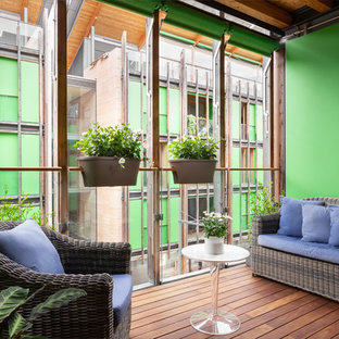 Ispirazione per un piccolo balcone design con un giardino in vaso, parapetto in vetro e un tetto a sbalzo