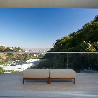 Example of a mid-sized trendy glass railing balcony design in Los Angeles with a roof extension