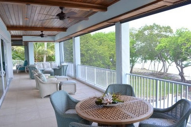 Example of a large beach style balcony design in Miami with a roof extension