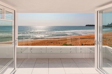シドニーにある低価格の小さなビーチスタイルのおしゃれなマンションのベランダ・バルコニー (オーニング・日よけ、ガラスフェンス) の写真