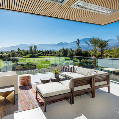 Example of a trendy glass railing balcony design in Orange County with a roof extension