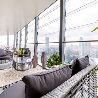 Design ideas for a medium sized contemporary glass railing balcony in London with a roof extension.