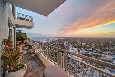 This is an example of a medium sized modern metal railing balcony in Miami with an awning.