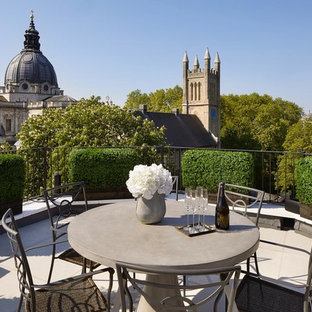 This is an example of a medium sized contemporary metal railing balcony in London with a potted garden and no cover.