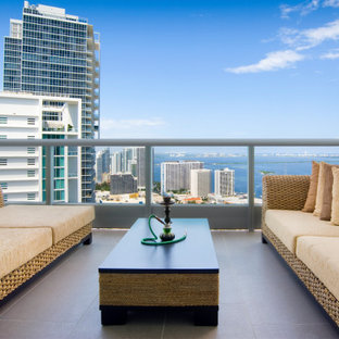 Cette image montre un grand balcon minimaliste d'appartement avec une extension de toiture et un garde-corps en métal.