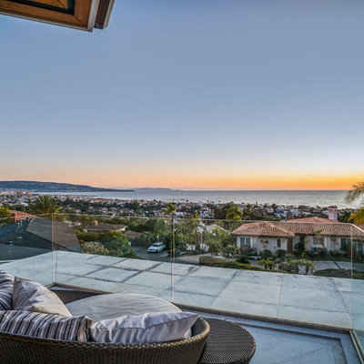 Large trendy glass railing balcony photo in Los Angeles with a roof extension