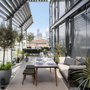 Expansive contemporary glass railing balcony in London with a potted garden and a pergola.