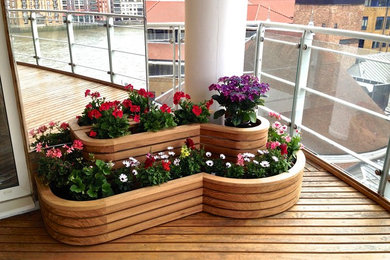 Photo of a large modern metal railing balcony in London with a potted garden and a roof extension.