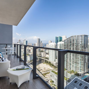 Trendy mixed material railing and apartment balcony photo in Miami with a roof extension