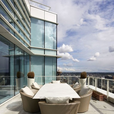 Example of a huge trendy metal railing balcony design in Vancouver with a roof extension