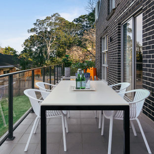 Contemporary balcony in Sydney with no cover and glass railing.