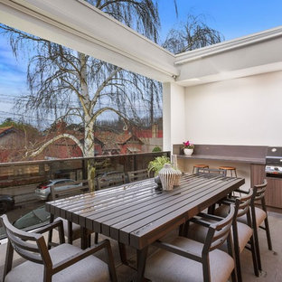 Design ideas for a contemporary balcony in Melbourne with an awning and glass railing.