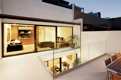 На фото: большой балкон и лоджия в стиле модернизм с стеклянными перилами без защиты от солнца