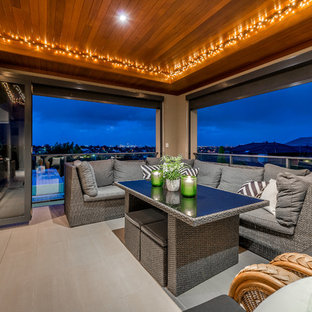 Photo of a contemporary balcony in Perth with a roof extension and glass railing.