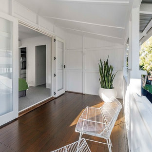 Inspiration for a contemporary balcony in Brisbane with a roof extension and wood railing.