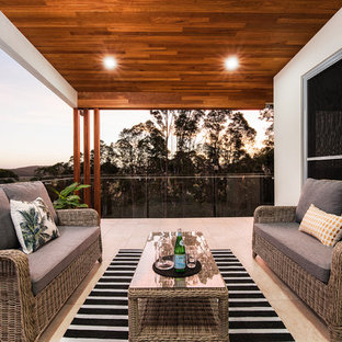 Photo of a beach style balcony in Brisbane with a roof extension and glass railing.