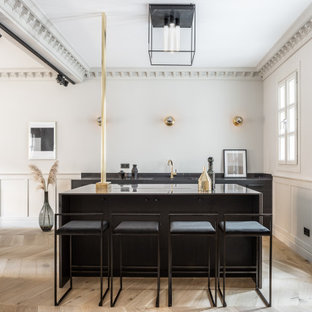 Foto de bar en casa con barra de bar de galera, escandinavo, con fregadero bajoencimera, armarios con paneles lisos, puertas de armario negras, suelo de madera clara, suelo beige y encimeras negras