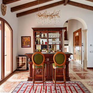 Imagen de bar en casa con barra de bar de galera, mediterráneo, con puertas de armario de madera en tonos medios, salpicadero con efecto espejo y suelo marrón