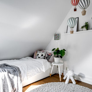 Inspiration för minimalistiska barnrum kombinerat med sovrum, med vita väggar, mellanmörkt trägolv och brunt golv