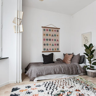 Foto på ett mellanstort minimalistiskt könsneutralt barnrum kombinerat med sovrum och för 4-10-åringar, med vita väggar, beiget golv och ljust trägolv
