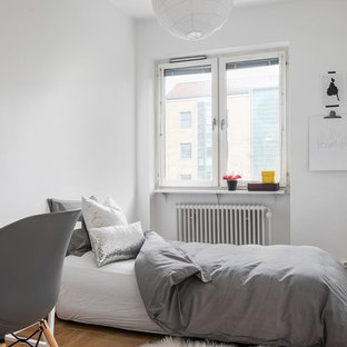 Foto på ett minimalistiskt barnrum kombinerat med sovrum, med vita väggar, mellanmörkt trägolv och brunt golv