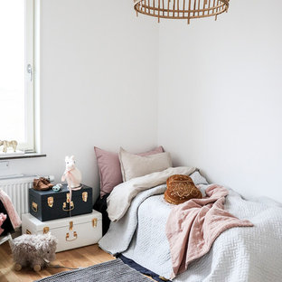 Bild på ett litet minimalistiskt flickrum kombinerat med sovrum och för 4-10-åringar, med vita väggar, mellanmörkt trägolv och beiget golv