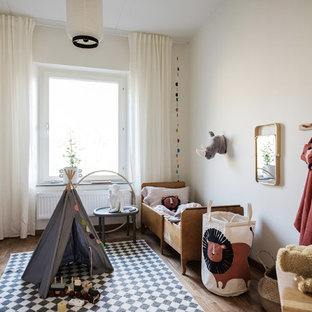 Inspiration för ett skandinaviskt könsneutralt småbarnsrum kombinerat med sovrum, med vita väggar och mellanmörkt trägolv