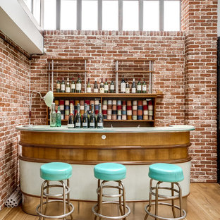 Aménagement d'un grand bar de salon linéaire industriel avec des tabourets, un placard sans porte, un sol beige, des portes de placard en bois brun, un sol en bois clair et un plan de travail blanc.